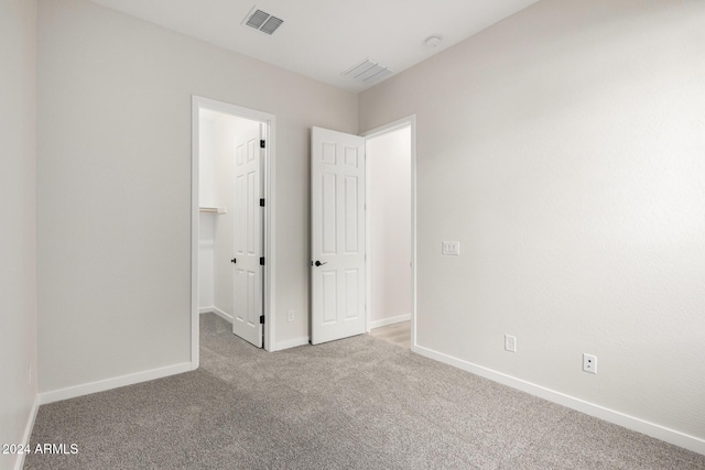 unfurnished bedroom with light carpet, a spacious closet, and a closet