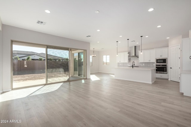 unfurnished living room with light wood-type flooring, plenty of natural light, and sink