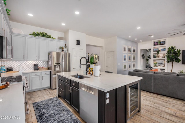 kitchen featuring wine cooler, sink, appliances with stainless steel finishes, an island with sink, and white cabinets