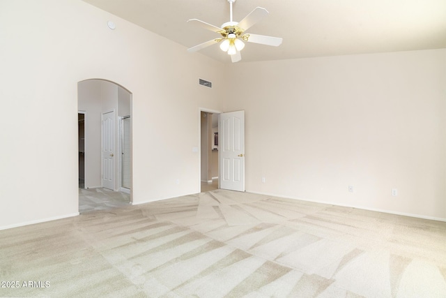 carpeted empty room featuring ceiling fan and a high ceiling