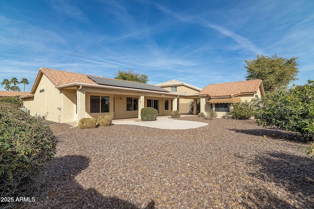 rear view of house featuring a patio area and solar panels