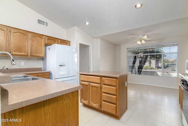 kitchen featuring a kitchen island, lofted ceiling, sink, white refrigerator with ice dispenser, and ceiling fan