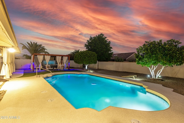 pool at dusk with a patio area and a gazebo