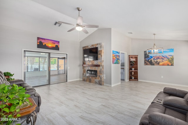 living room featuring ceiling fan with notable chandelier, a fireplace, and vaulted ceiling