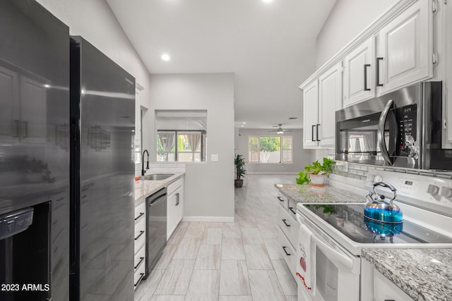 kitchen featuring stainless steel appliances, light stone counters, sink, ceiling fan, and white cabinets