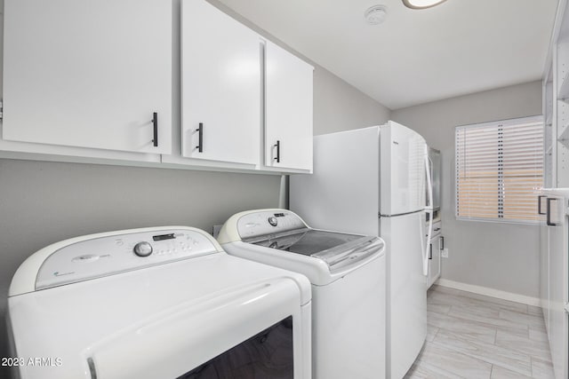 washroom with washer and dryer and cabinets