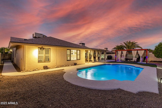 pool at dusk with a gazebo and a patio