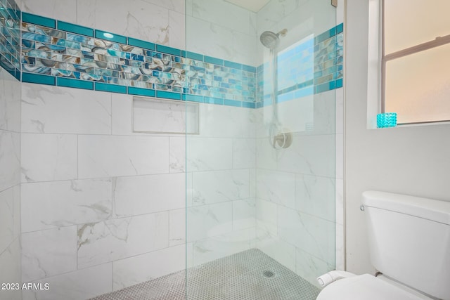 bathroom featuring toilet and a tile shower