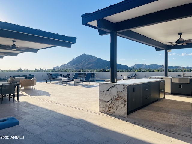 view of patio with ceiling fan, a mountain view, an outdoor hangout area, and a sink