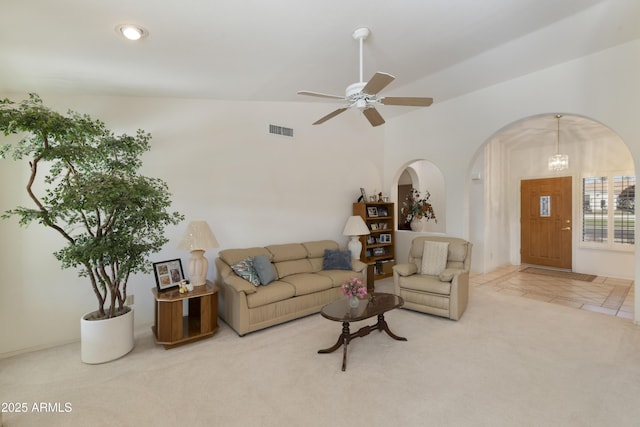 carpeted living room with ceiling fan with notable chandelier and vaulted ceiling