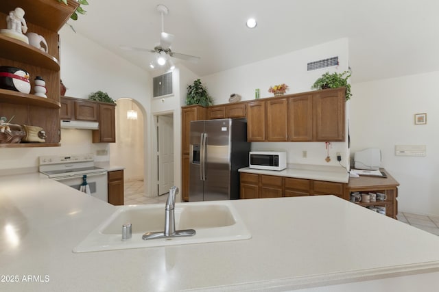 kitchen with lofted ceiling, sink, white appliances, ceiling fan, and kitchen peninsula