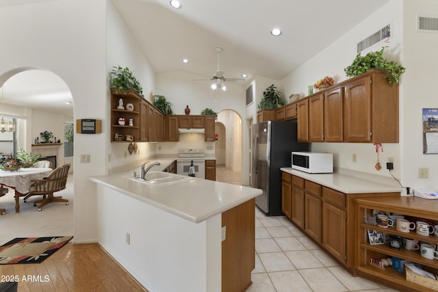 kitchen with sink, white appliances, kitchen peninsula, ceiling fan, and a high ceiling