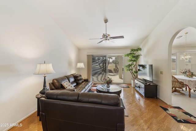 living room featuring plenty of natural light, ceiling fan with notable chandelier, and light wood-type flooring