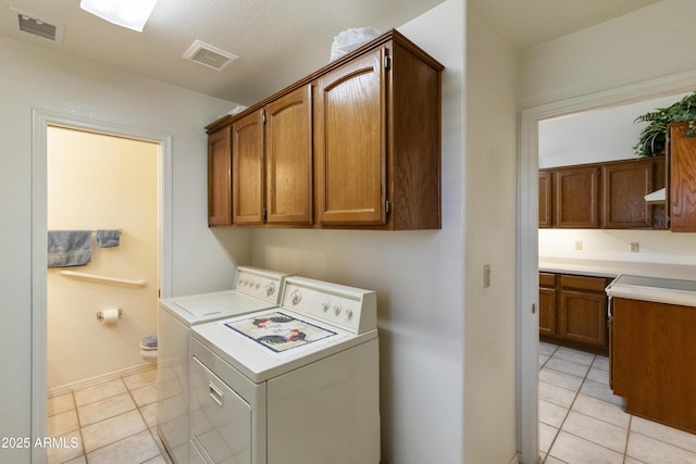 laundry room with cabinets, washing machine and clothes dryer, and light tile patterned flooring