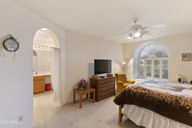 bedroom featuring ceiling fan, ensuite bath, and light carpet