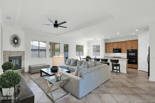 7917 S 32nd Ter, Phoenix, AZ 85042 - living room with a tile fireplace, light tile patterned floors, ceiling fan, and a tray ceiling