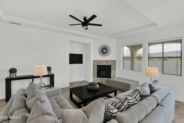 7917 S 32nd Ter, Phoenix, AZ 85042 - tiled living room with ceiling fan, a fireplace, and a tray ceiling