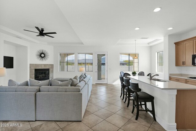 7917 S 32nd Ter, Phoenix, AZ 85042 - living room with light tile patterned flooring, sink, a tray ceiling, ceiling fan, and a fireplace