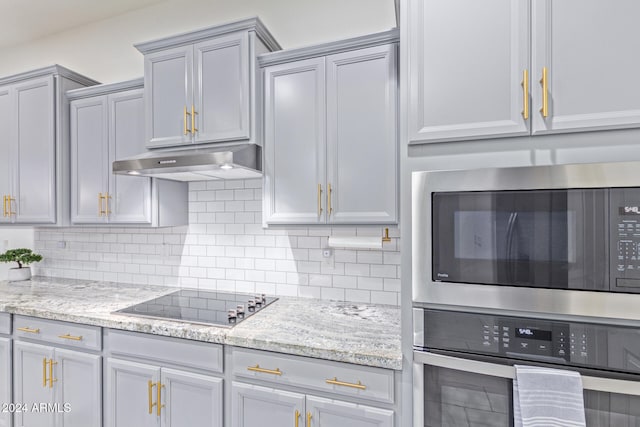 kitchen with gray cabinetry, decorative backsplash, light stone counters, and stainless steel appliances