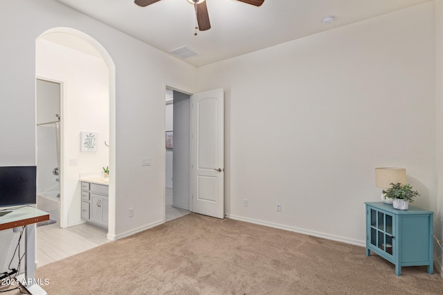 interior space featuring ceiling fan, light carpet, and connected bathroom