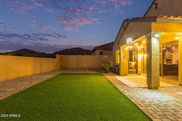 yard at dusk featuring a mountain view and a patio