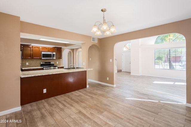 kitchen with light wood-type flooring, appliances with stainless steel finishes, decorative light fixtures, and a notable chandelier