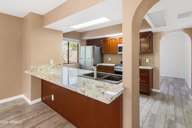 kitchen featuring kitchen peninsula, appliances with stainless steel finishes, and light hardwood / wood-style floors