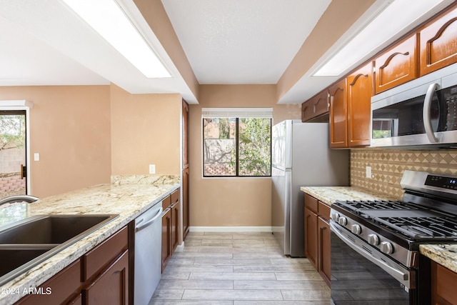 kitchen with light wood-type flooring, stainless steel appliances, a healthy amount of sunlight, and tasteful backsplash