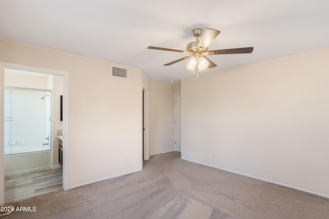 interior space with light colored carpet, ceiling fan, and ensuite bath