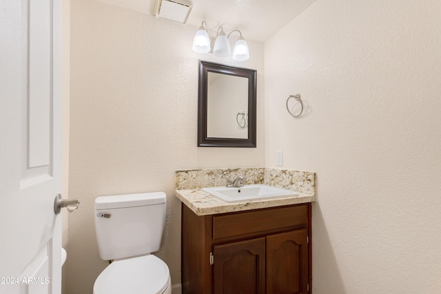 bathroom featuring toilet, vanity, and a textured ceiling