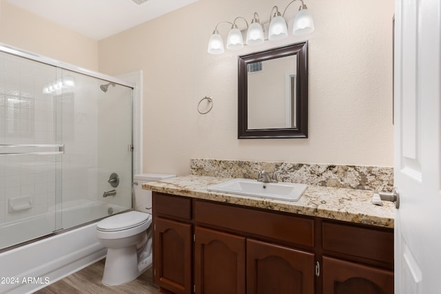 full bathroom featuring toilet, vanity, bath / shower combo with glass door, and hardwood / wood-style floors