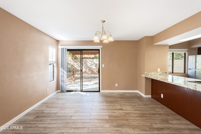 unfurnished dining area featuring a notable chandelier and light hardwood / wood-style flooring