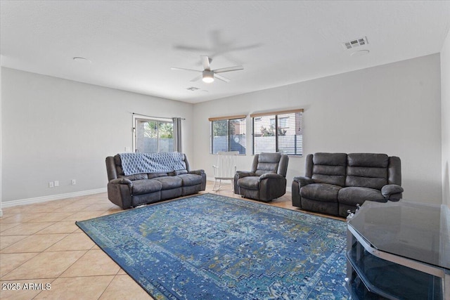 living area featuring light tile patterned flooring, visible vents, ceiling fan, and baseboards