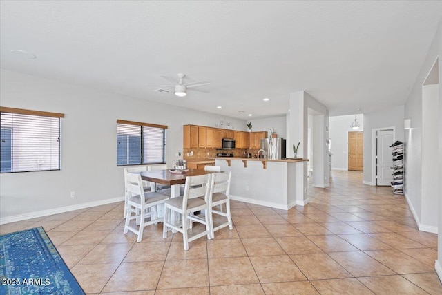 dining area with a ceiling fan, light tile patterned floors, a healthy amount of sunlight, and baseboards