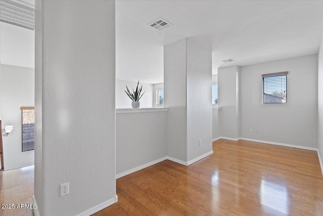 unfurnished room featuring visible vents, baseboards, and wood finished floors