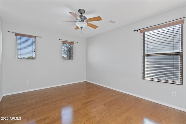 unfurnished room with visible vents, baseboards, a ceiling fan, and wood finished floors