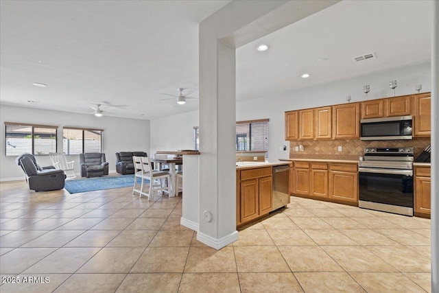 kitchen with visible vents, light tile patterned floors, decorative backsplash, stainless steel appliances, and a sink