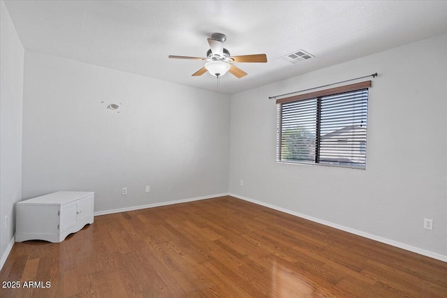 unfurnished room featuring a ceiling fan, wood finished floors, visible vents, and baseboards