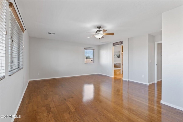 spare room with baseboards, wood finished floors, visible vents, and ceiling fan