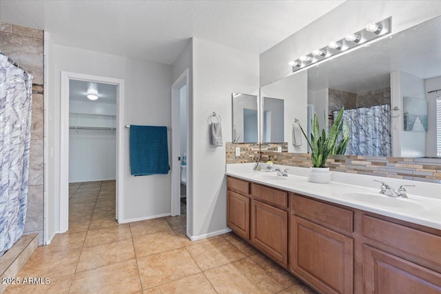 bathroom featuring tile patterned flooring, double vanity, tiled shower, and a sink