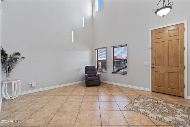 foyer featuring light tile patterned flooring, baseboards, and a towering ceiling