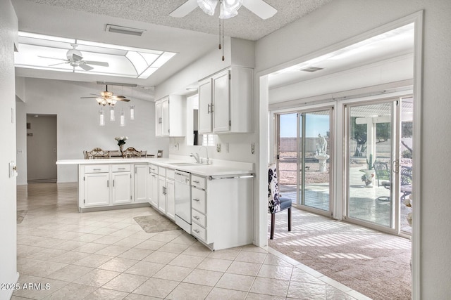 kitchen with kitchen peninsula, dishwasher, light colored carpet, white cabinetry, and a textured ceiling