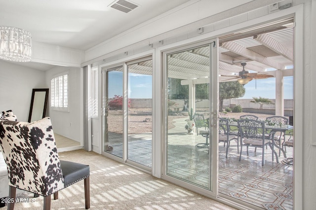 doorway featuring ceiling fan with notable chandelier and light colored carpet