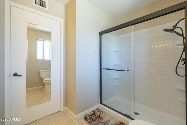 bathroom featuring toilet, an enclosed shower, and tile patterned flooring