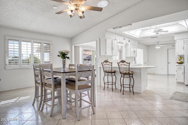 tiled dining space featuring ceiling fan, a textured ceiling, and lofted ceiling