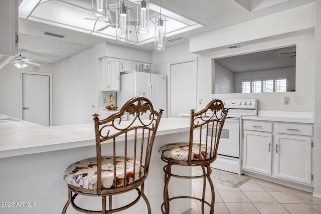 kitchen featuring white appliances, white cabinets, pendant lighting, ceiling fan, and a breakfast bar area