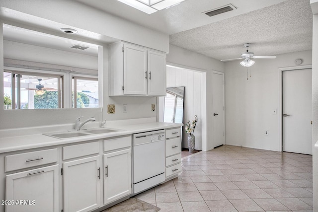 kitchen featuring white dishwasher, a textured ceiling, white cabinetry, light tile patterned floors, and sink