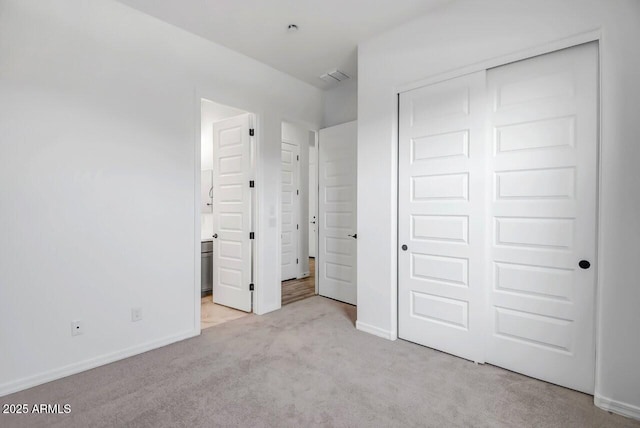 unfurnished bedroom with connected bathroom, light colored carpet, and a closet