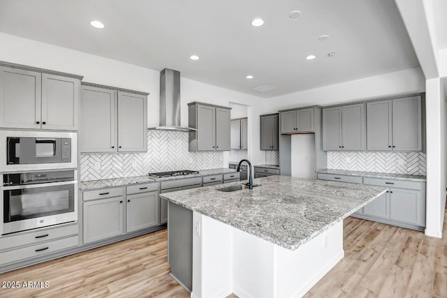 kitchen featuring stainless steel appliances, sink, wall chimney range hood, and gray cabinetry