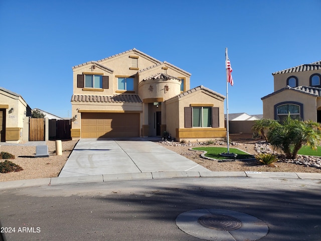 mediterranean / spanish house with a tile roof, fence, concrete driveway, and stucco siding